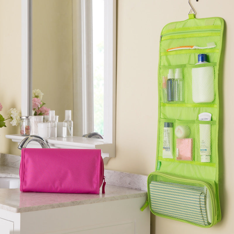 Green hanging toiletry bag with pink pouch on a bathroom counter