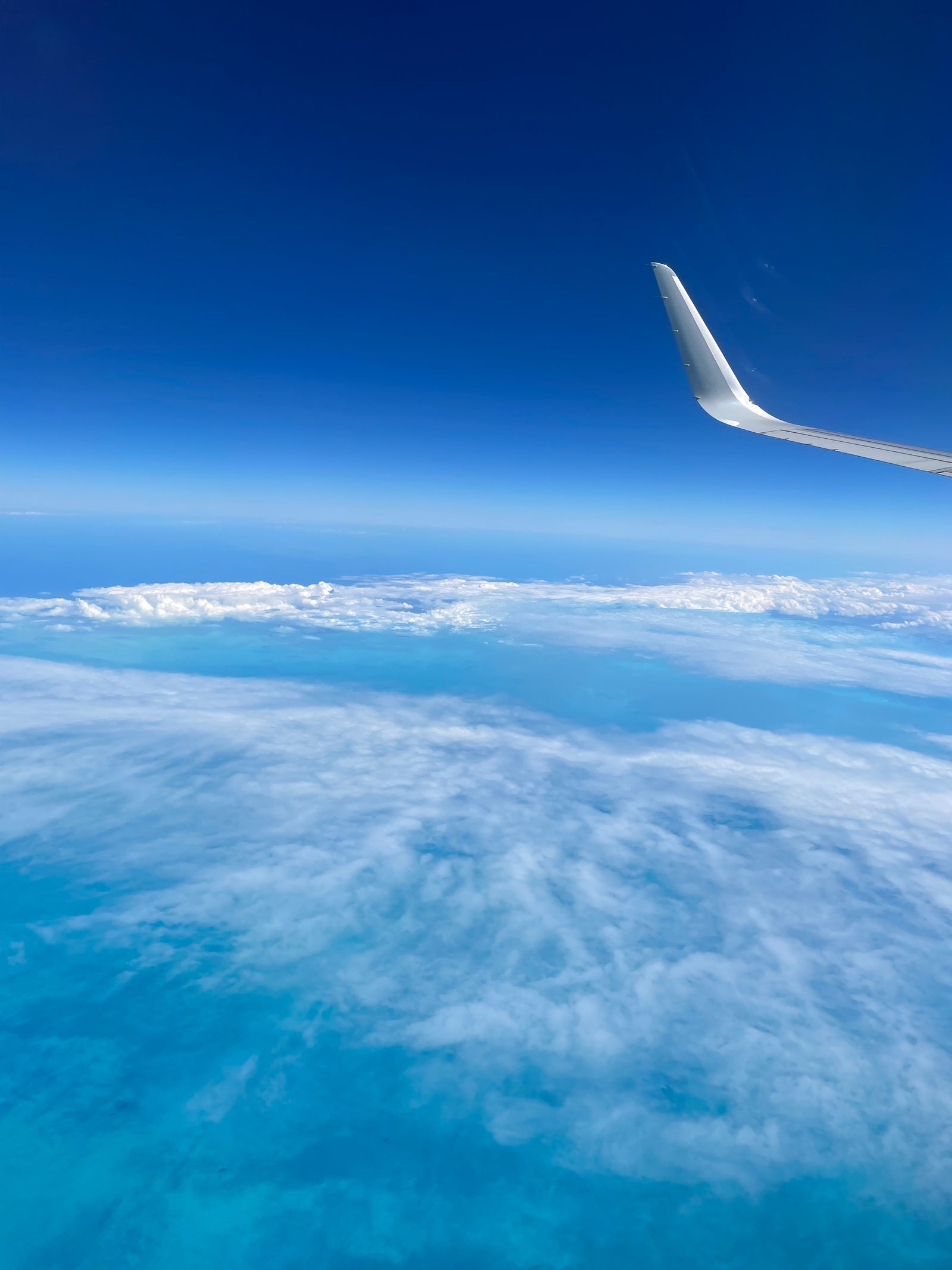 Airplane wing above the clouds with a clear blue sky