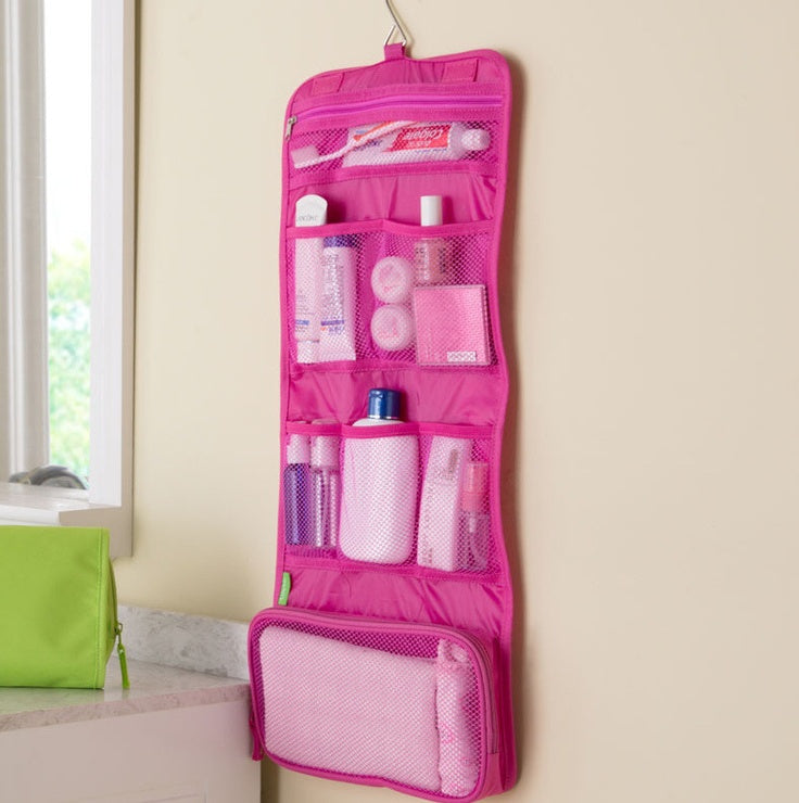 Pink hanging organizer with toiletries on a beige wall