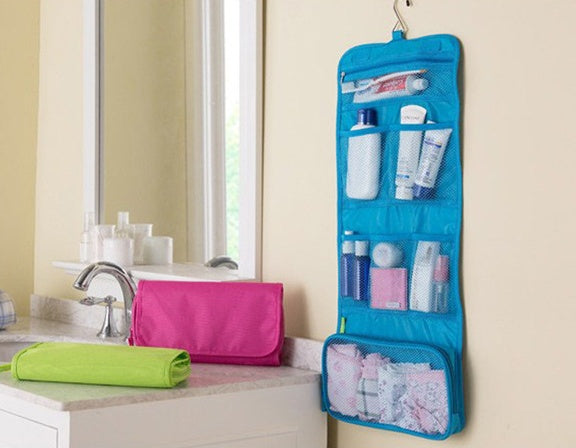 Blue hanging toiletry organizer with various items on a bathroom counter.