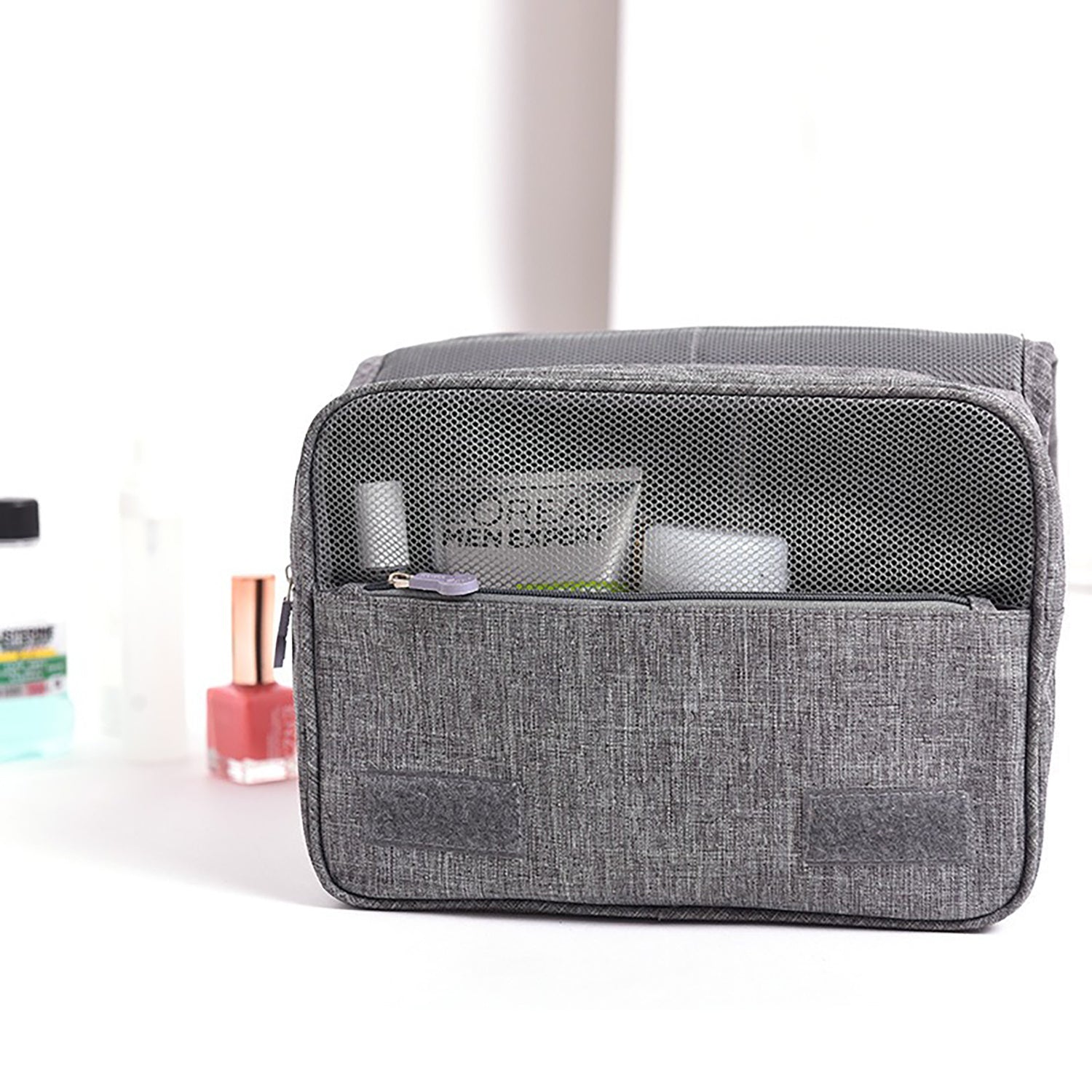 Gray toiletry bag with cosmetic products on a white background