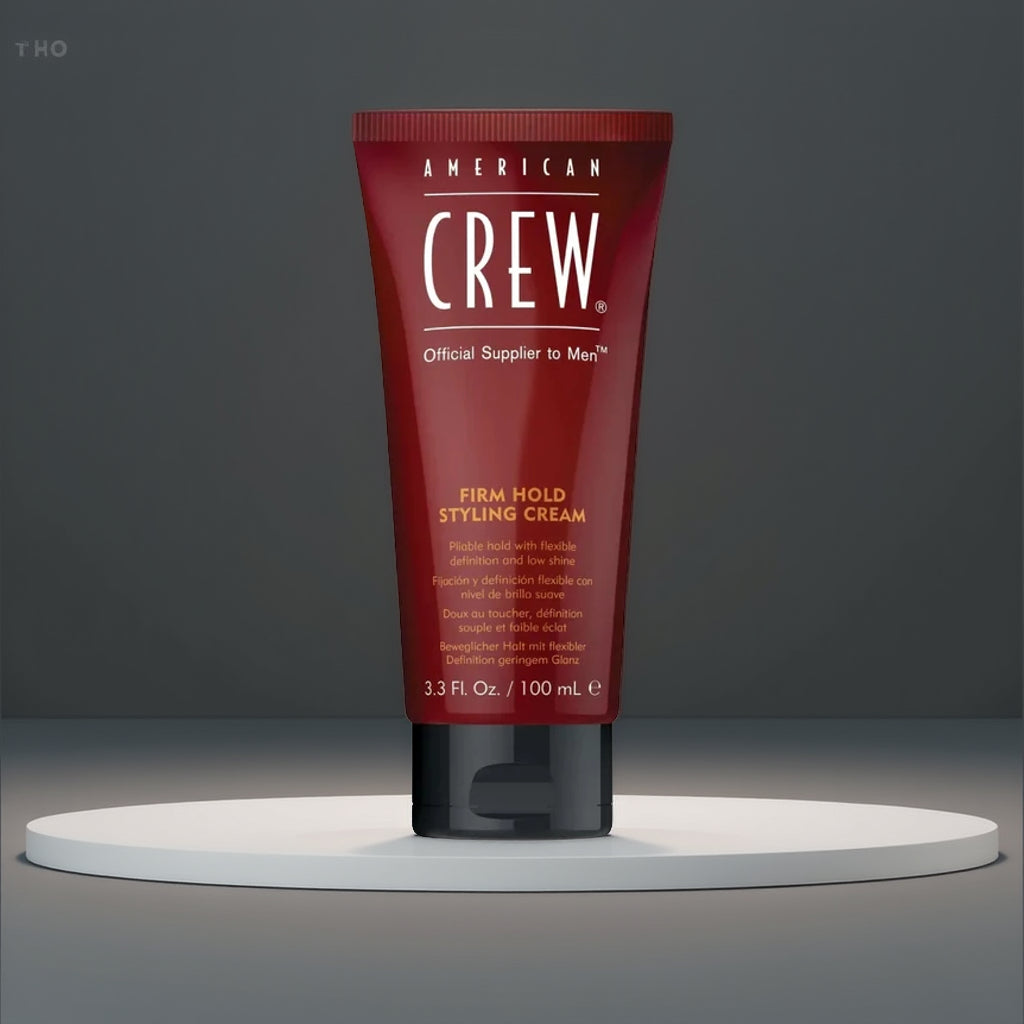 Red travel-sized tube of American Crew styling cream on a gray background