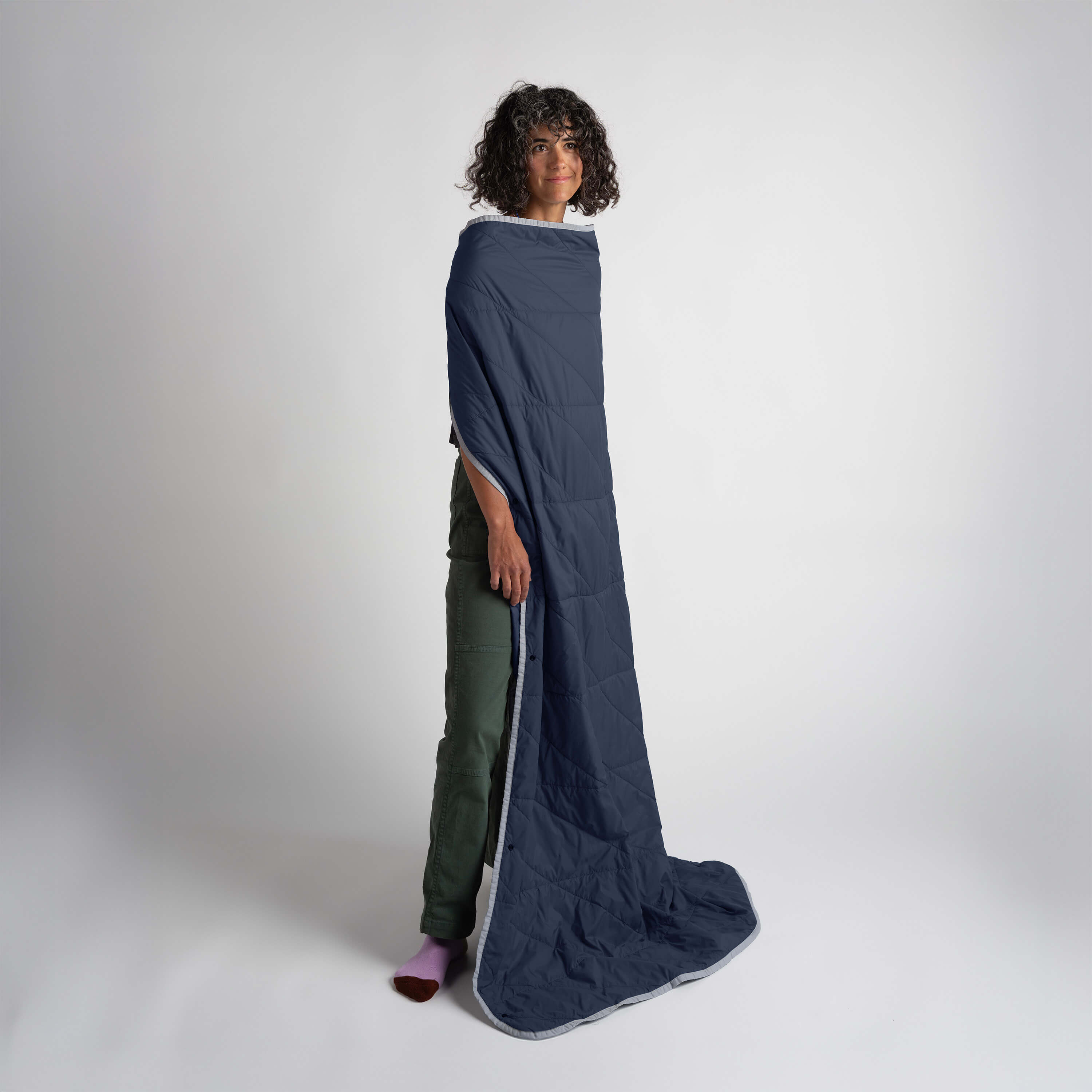 Person wearing a long navy-blue blanket on a white background