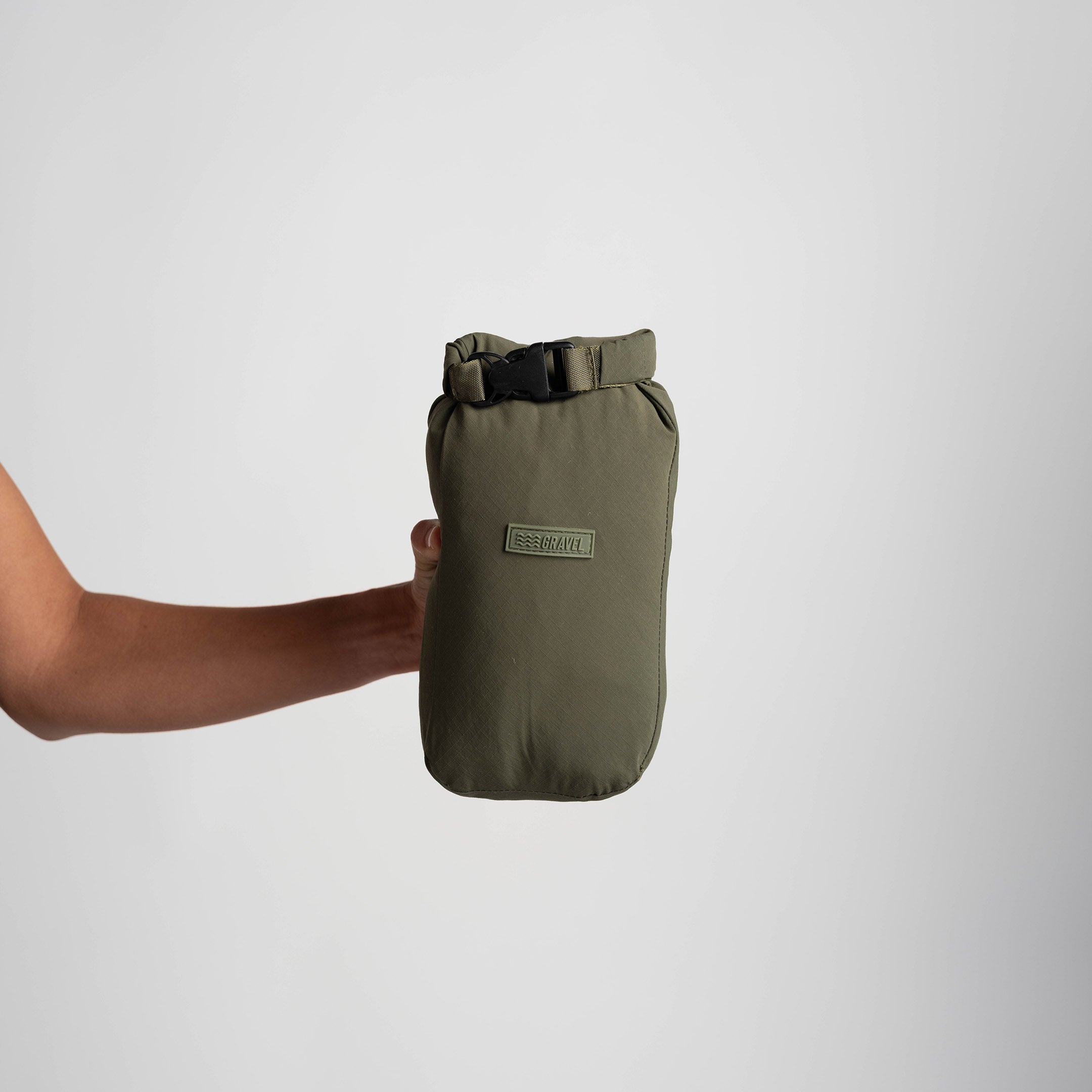 Person holding a green waterproof bag against a white background