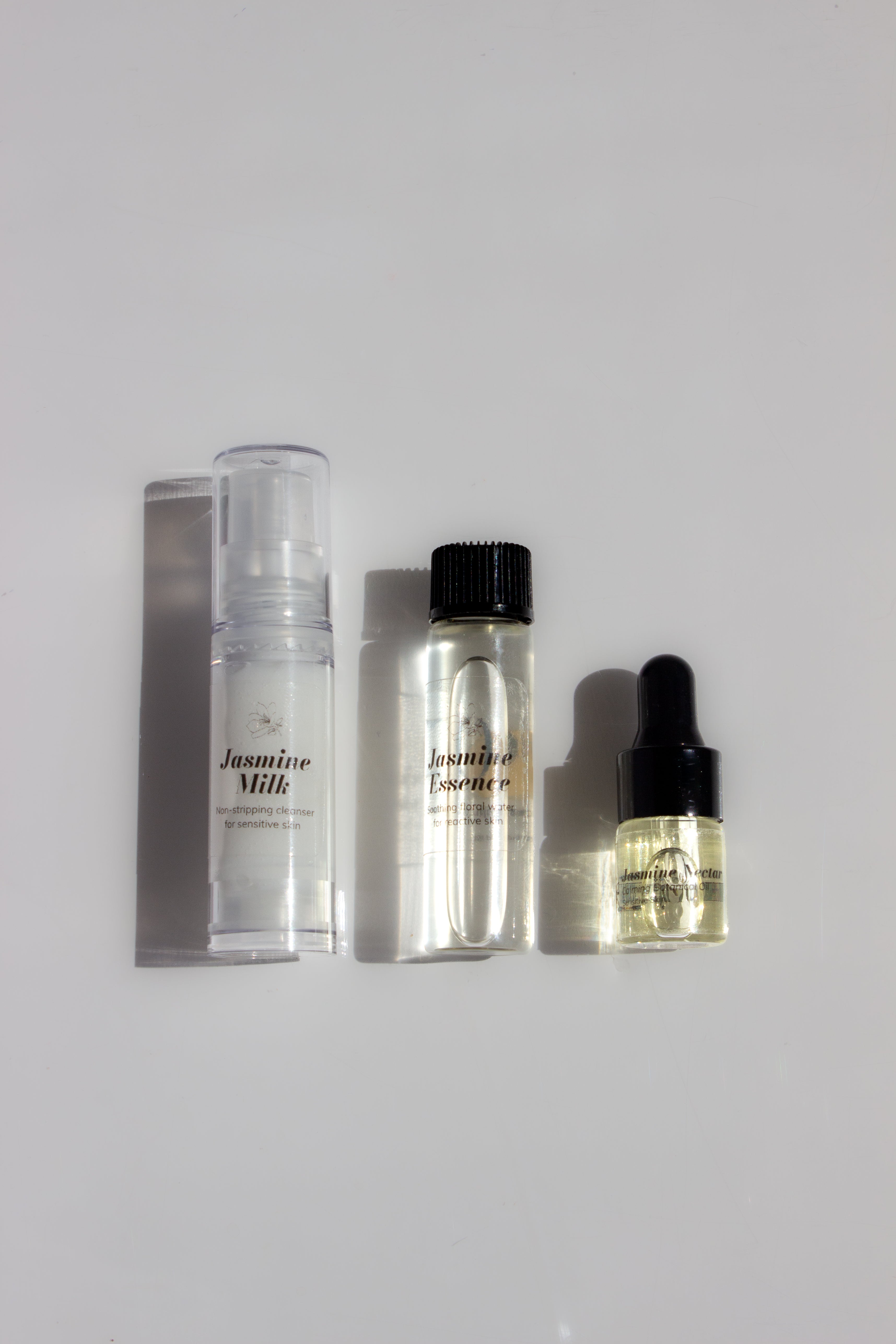 Set of skincare products including a spray, bottle, and dropper on a light gray background