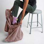 Person sitting on a stool with a quartz blanket, wearing green pants and purple socks.