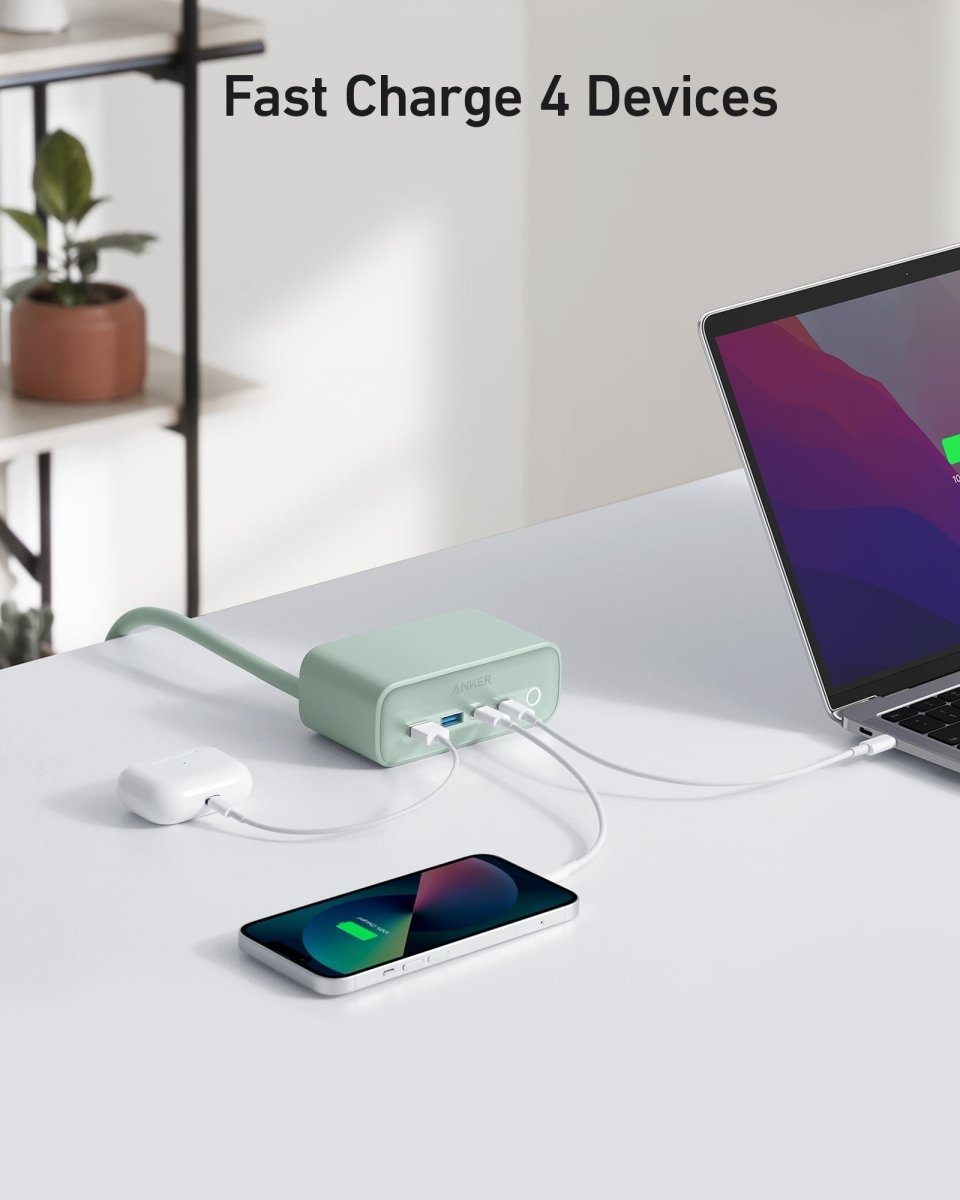 Green USB-C hub charging multiple devices on a white surface with a laptop in the background.