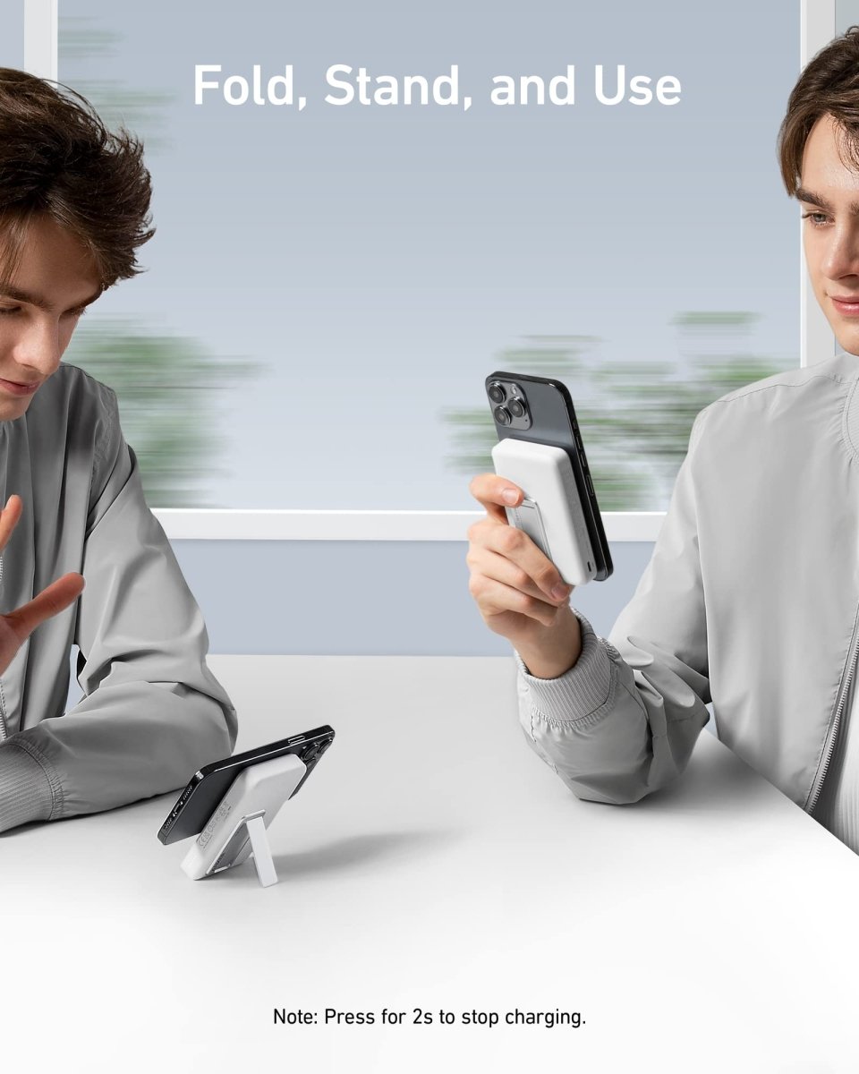 Two people using a phone with a stand and charger, sitting at a table.