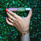 Hand holding a small bottle with a green leafy background