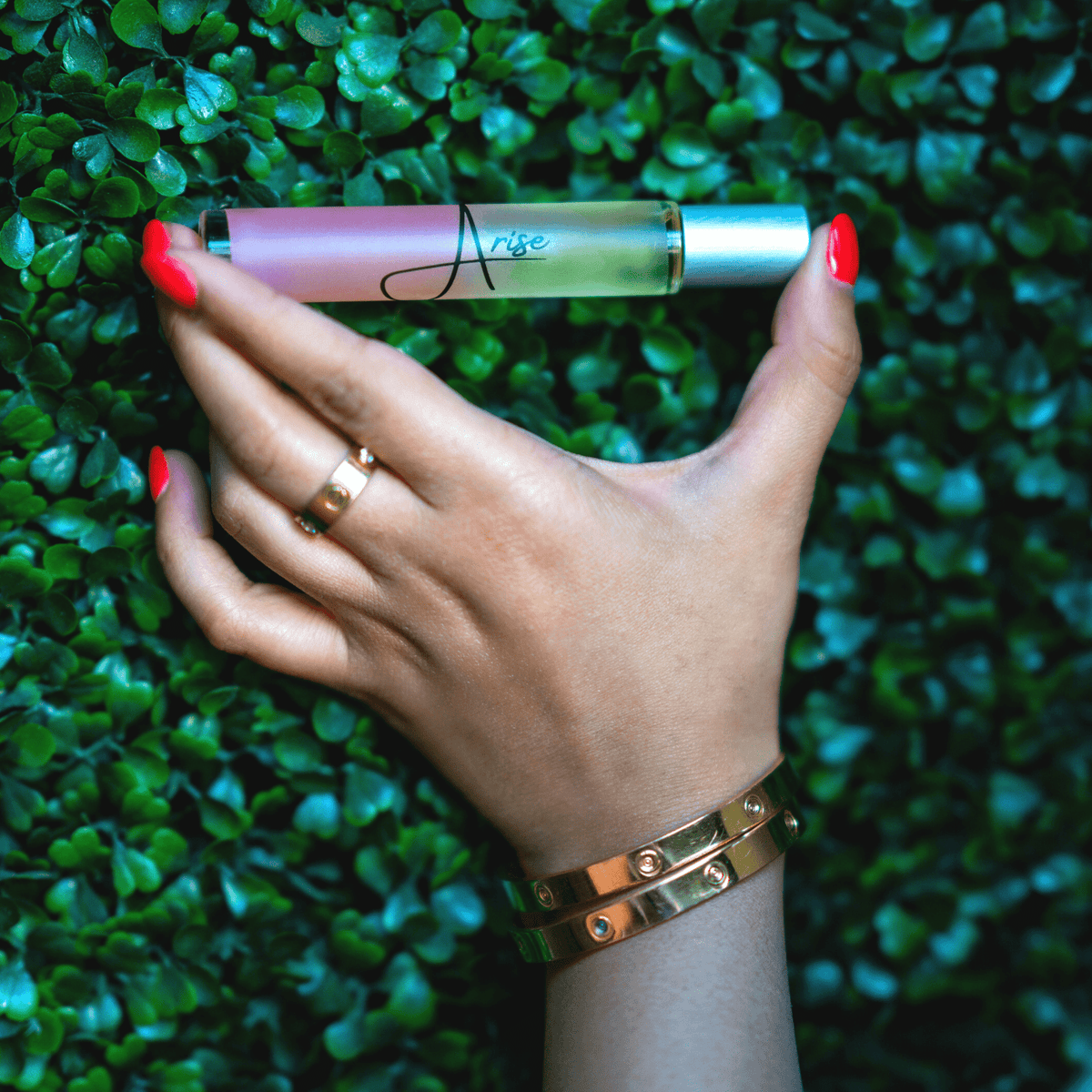 Hand holding a small bottle with a green leafy background