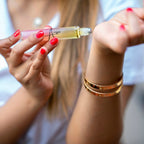 Close-up of a woman's hands holding a small rollerball bottle with a blurred background