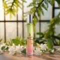 Perfume bottle with floral design on a wooden surface with greenery in the background