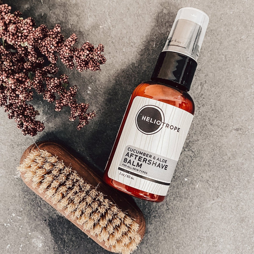 Heliotrope cucumber & aloe aftershave balm bottle with brush on a gray surface