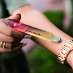 Roll-on bottle of perfume with a gradient design held by a person outdoors.