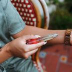 Person applying perfume to their arm with a chair and blurred background