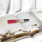 Perfume bottle labeled 'Known' on an open magazine with a blurred indoor setting