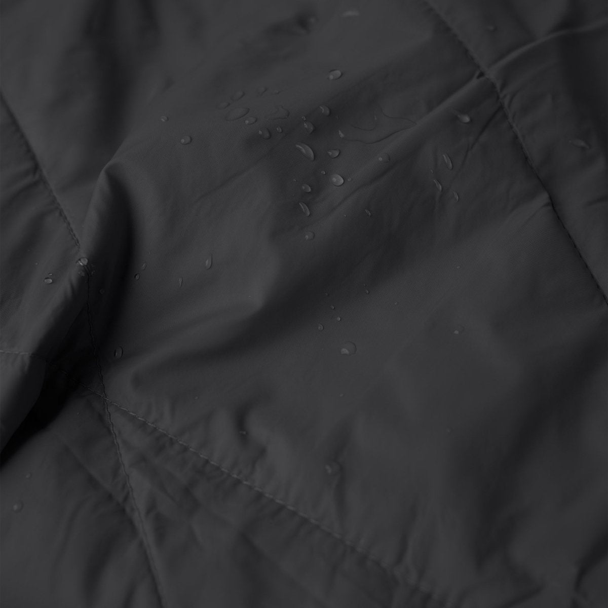 Close-up texture of Layover™ XL Travel Blanket | Black with water droplets.