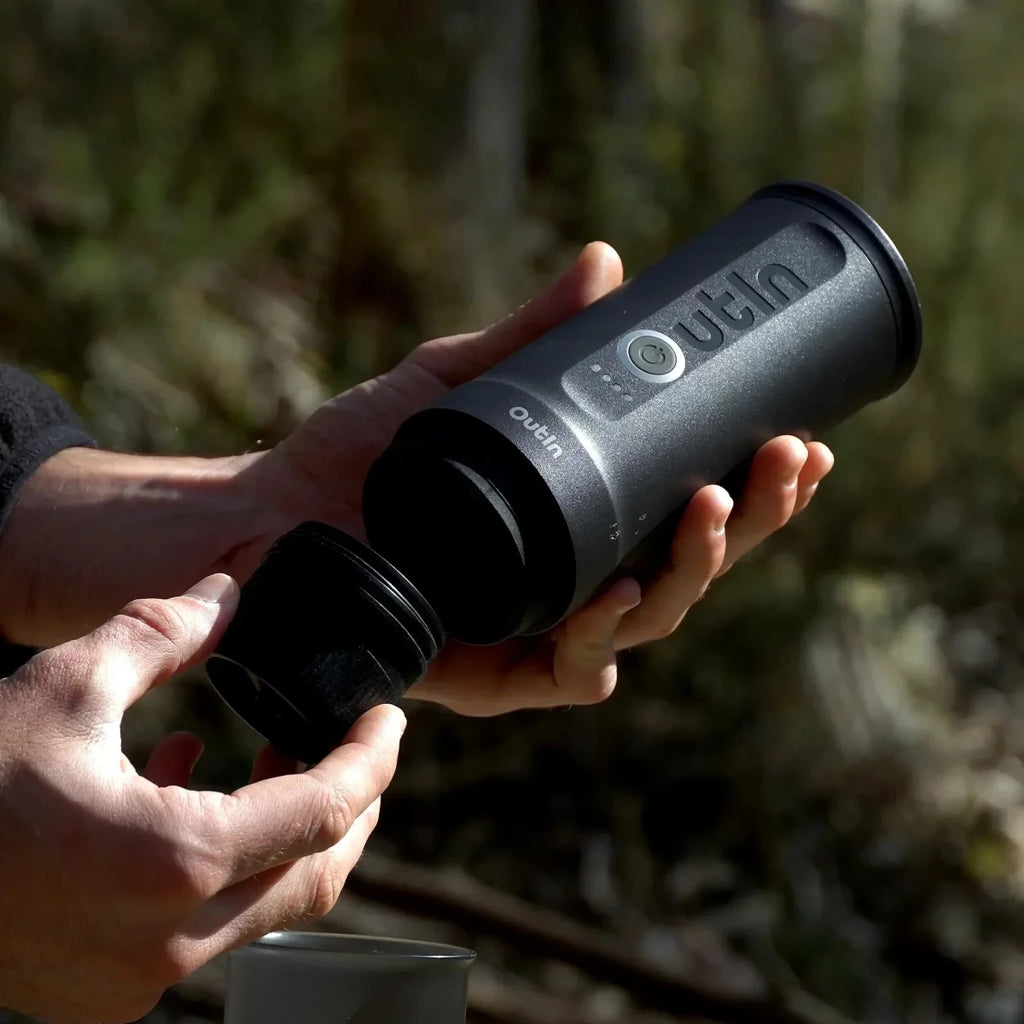 Person holding a black Outlin device in a natural setting
