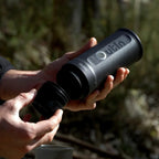 Person holding a black Outlin device in a natural setting