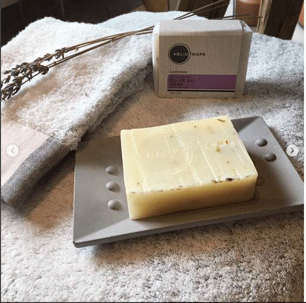 Heliotrope Nourishing Olive Oil Soap on a gray plate, TSA approved toiletries