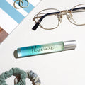 Roll-on bottle with 'Persevere' text, glasses, and scrunchies on a textured surface
