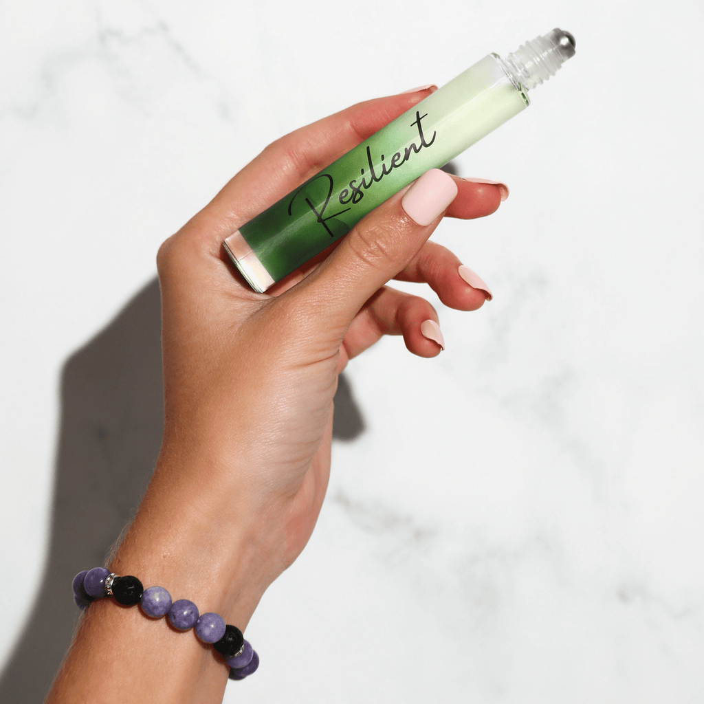 Hand holding a green rollerball labeled 'Resilient' against a white background