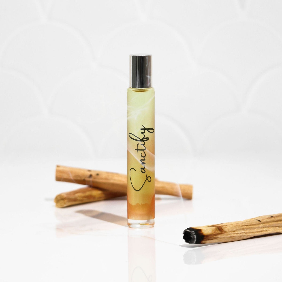 Small bottle labeled 'Sanctify' with two wooden sticks on a white background