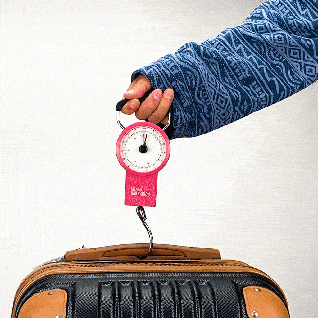 The luggage scale in use, being shown lifting the suitcase up.