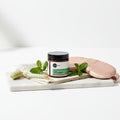 Sunflower & Shea Butter Foot Treatment – Cooling Botanical Cream (4 oz) on a marble tray with mint and beauty tools.