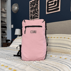 Pink backpack with 'COR' branding on a bed in a bedroom setting