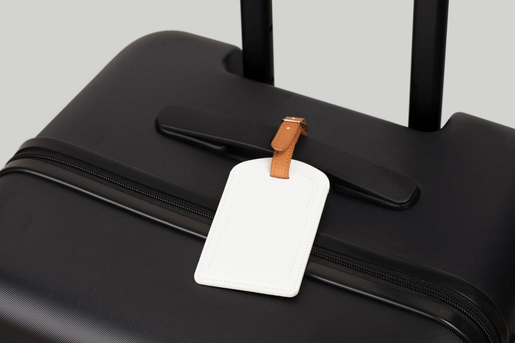 The Luggage Tag on a black suitcase for easy travel identification.