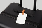 The Luggage Tag on a black suitcase for easy travel identification.