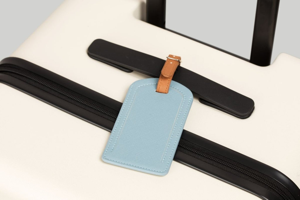 The Luggage Tag in blue on a suitcase for travel.