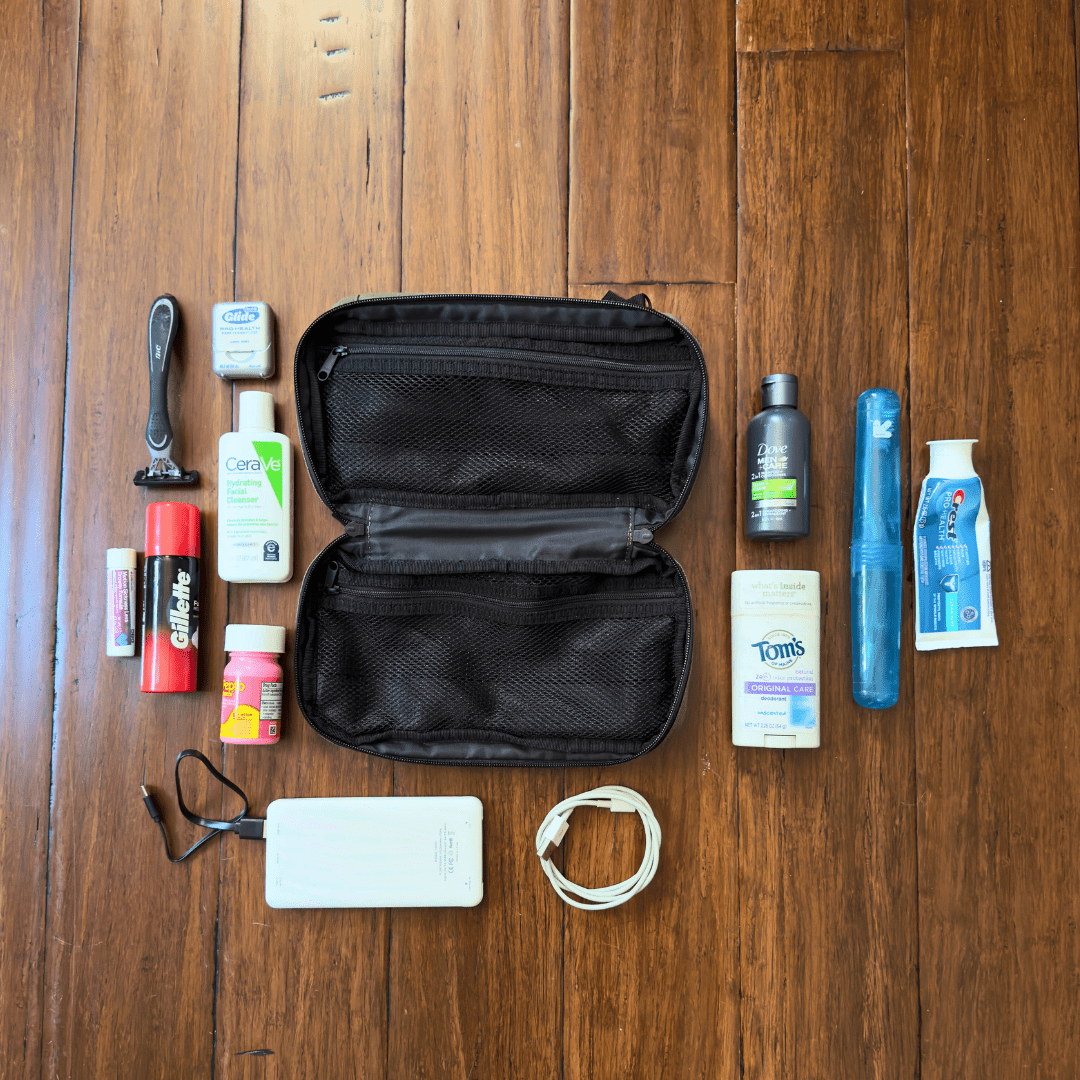 Collection of toiletries and a black travel case on a wooden surface